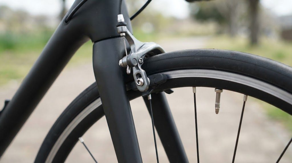 ロードバイクのリムブレーキのキャリパーと、リムの側面に当たる黒いゴムのブレーキシューの接写